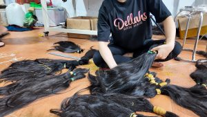 showing a woman in a Human hair extensions factory in cambodia holding raw donor cut hair extensions. Dellahs raw hair sell their hair worldwide and have warehouse in london